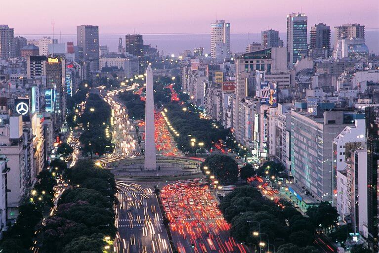 Sunset aerial view of traffic and buildings along Avenida 9 de Julio and around the Obelisk in Buenos Aires