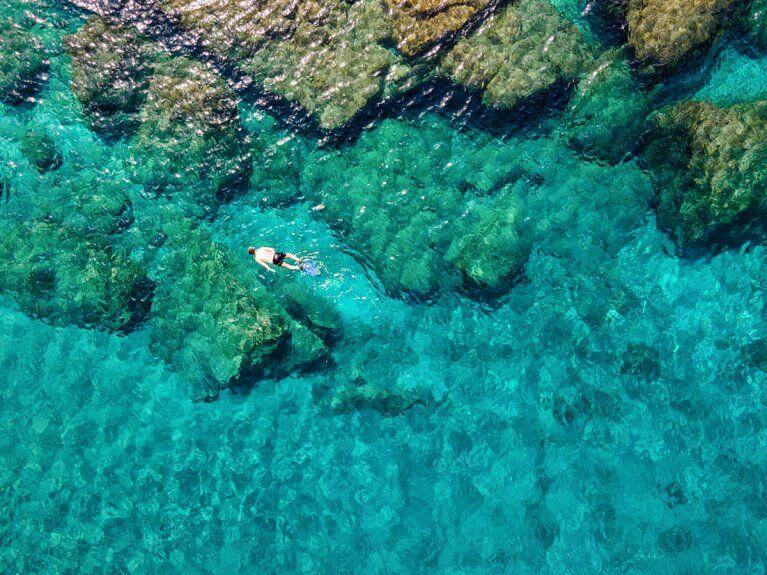 Aerial view of man snorkeling in clear blue waters of the Aegean sea